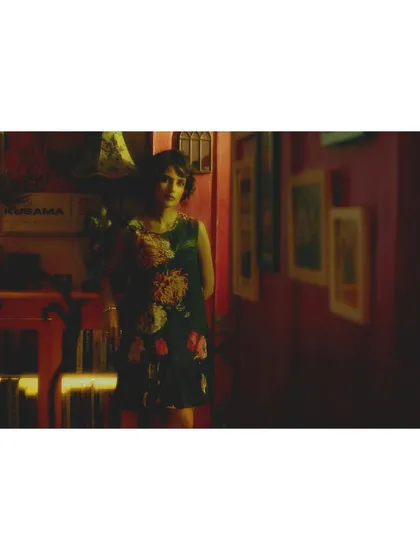 A wide shot establishing the 'Room of Memories'. The styling of the set, with its vintage decor and warm lighting, is as important as the fashion in telling the story.