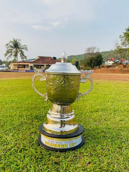 The runner-up trophy for the Goa Premier League, standing tall on the lush green Arlem Ground. A symbol of a hard-fought tournament.