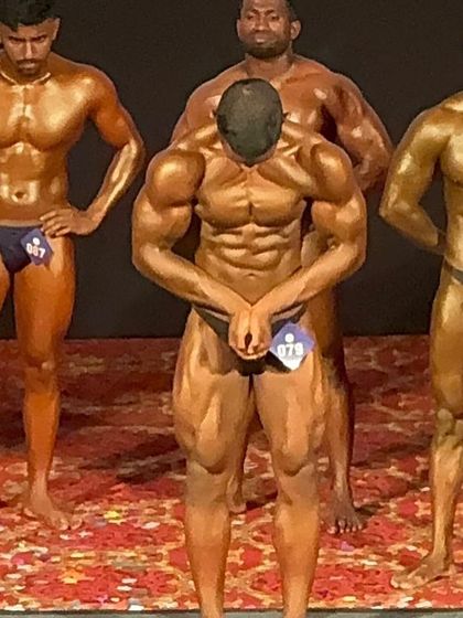 An 18-year-old natural athlete hitting a most muscular pose on stage. We work extensively on posing to make sure even young competitors look like seasoned pros.