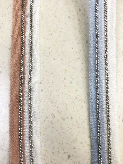 A pair of simple yet elegant trims featuring a delicate metal ball chain stitched onto a fabric base. Available in different colors, this is a subtle way to add a metallic accent to garments.