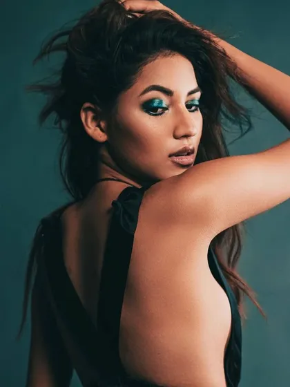 Another shot of the backless black top, this time with a pop of color from the blue eyeshadow. It shows how makeup and styling can work together to create a cohesive and impactful look.