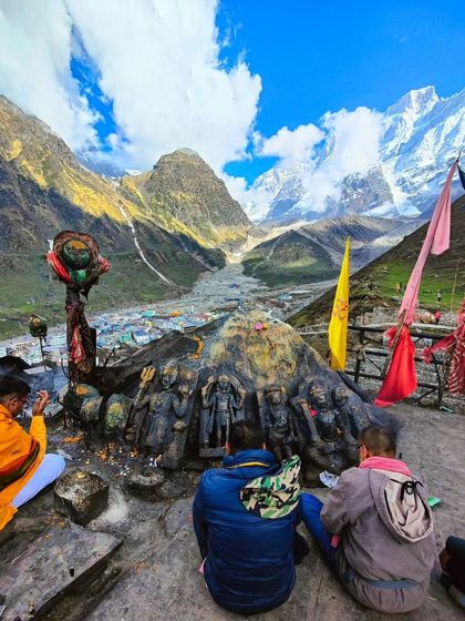 Devotees praying with a panoramic view of the Kedarnath valley and temple behind them. This photo captures the essence of pilgrimage: faith set against the immense scale of nature.