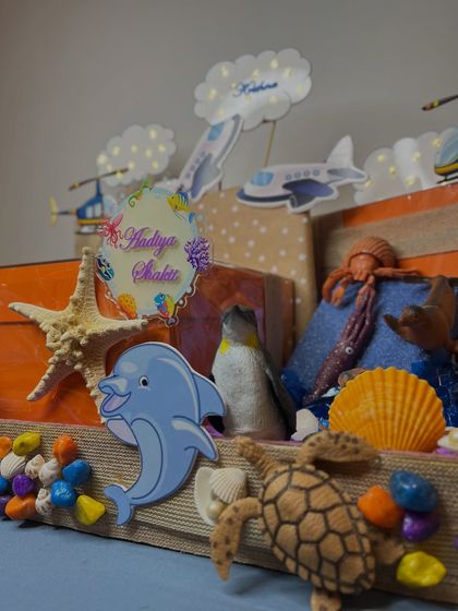A close-up of the 'sea' part of the hamper, with a dolphin, turtle, and personalized 'Aadiya Shakti' plaque.