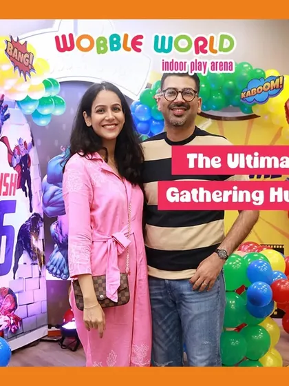A couple standing proudly in front of their child's superhero party decor. We are the ultimate gathering hub for your family's special events.