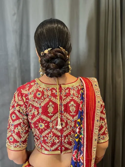 A classic braided bun with a simple gold accessory, created for a traditional Patola saree look. This updo is all about timeless elegance and cultural grace.