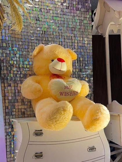 It's the small details that make a difference. A soft teddy bear sits on a decorative drawer, adding a sweet and personal touch to the large-scale baby shower setup.