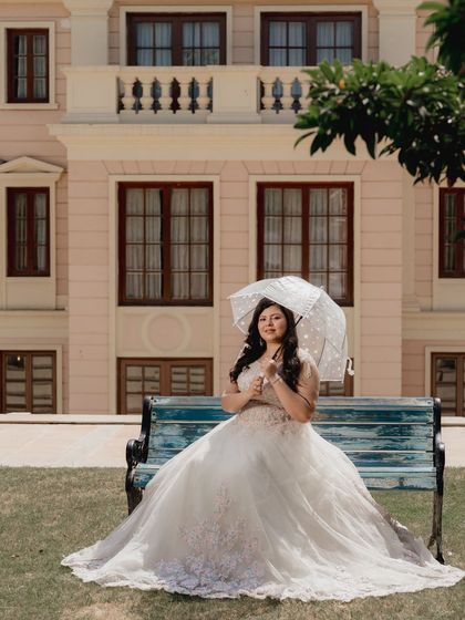 A beautiful solo shot of the bride in her princess gown, sitting on a bench in front of a grand building. This image is all about elegance and grace.
