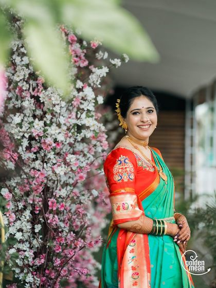 A bride posing next to a beautiful floral arrangement.