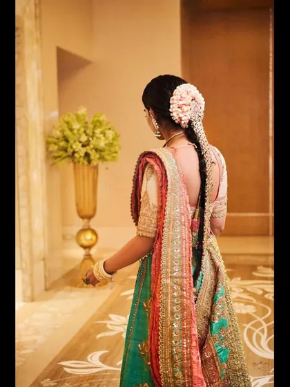 The back view of the Anuradha Vakil lehenga, showing the beautiful floral gajra and the elegant fall of the dupatta. This is a great example of traditional Indian hairstyling paired with couture.