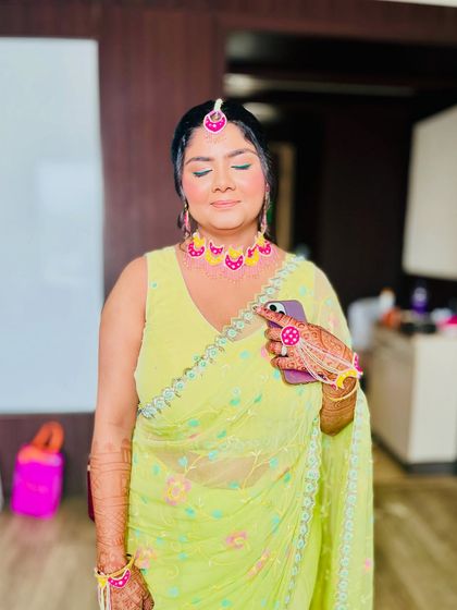 A soft, glowing makeup look for the Haldi ceremony. The focus is on fresh skin and subtly defined eyes, letting the vibrant outfit and jewelry shine.