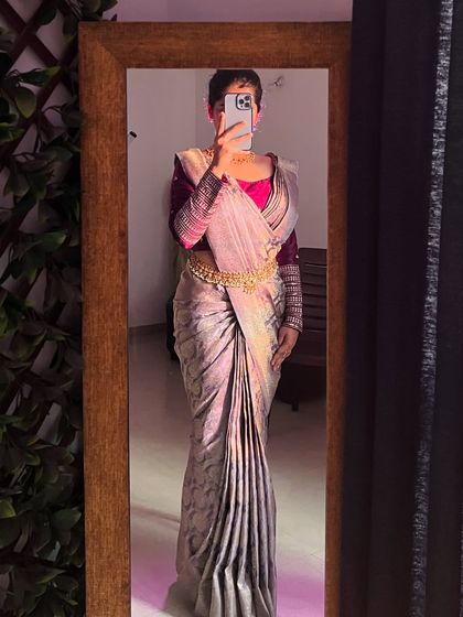 A modern take on saree draping, captured in a mirror selfie. The pleats are sharp and the pallu is styled to create a chic, contemporary silhouette.