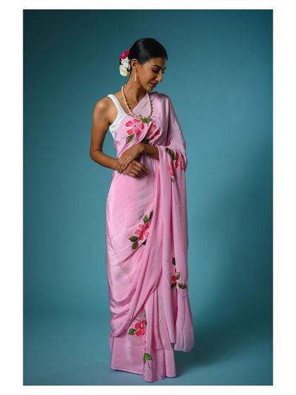 A full-length shot showing the elegant movement of the pink saree. This helps customers imagine how the fabric will feel and move.