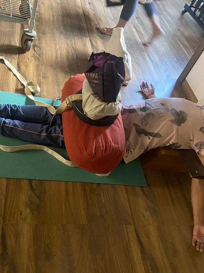 A therapeutic setup for the lower back and hips. The student is resting on a bench with bolsters and belts to decompress the lumbar spine.