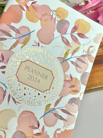 A close-up of the gold-foiled cover of our 'Continuity of Moons' planner. It’s all about celebrating the cycles of life and the celestial blessings that guide us.