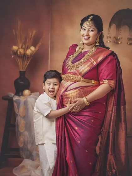 The little one can't hide his excitement. This family shot is so full of personality, with the older brother hugging his mom's baby bump with a huge, happy grin.
