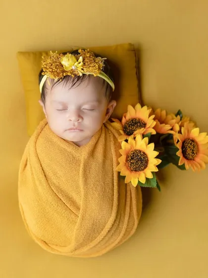 A little ray of sunshine, this baby is wrapped in a golden yellow swaddle with matching sunflowers.