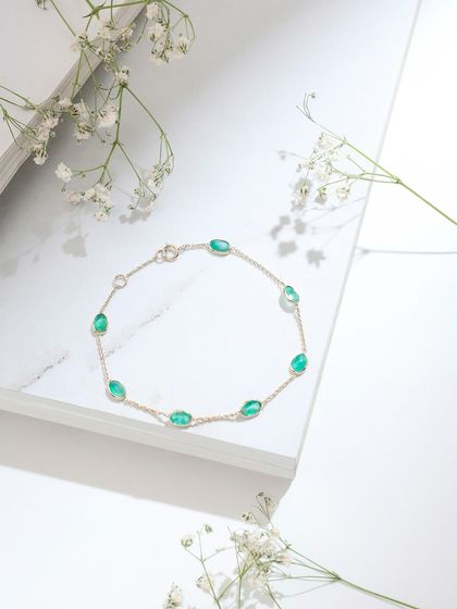 A product shot of the oval-cut emerald bracelet, laid out to showcase its simple, elegant design.