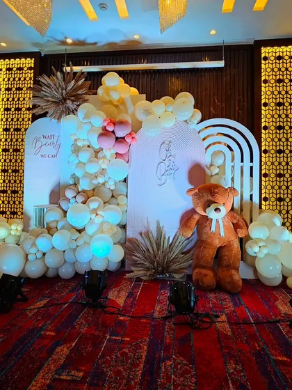 A cozy and elegant teddy bear baby shower at Fariyas Hotel. This design uses a warm, neutral color palette with soft lighting and a large teddy bear to create an inviting atmosphere.