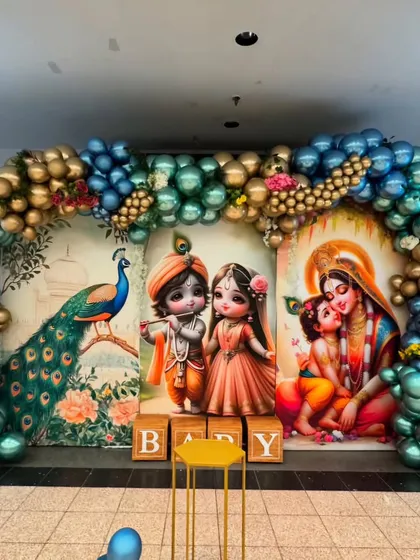 Celebrate your baby's arrival with a traditional Krishna-themed ceremony. This vibrant setup features beautiful illustrations of Lord Krishna and Yashoda, a magnificent peacock, and a grand balloon arch in metallic blues and golds, perfect for a Seemant Sanskar or naming ceremony.