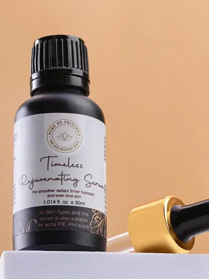 A close-up of Pure by Priyanka's "Timeless Rejuvenating Serum." The dark bottle and gold-accented dropper convey a sense of luxury and potency.