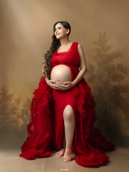 A confident and radiant solo maternity portrait in our studio. The vibrant red ruffled gown and classic painted backdrop combine to create a stunning piece of fine art photography.