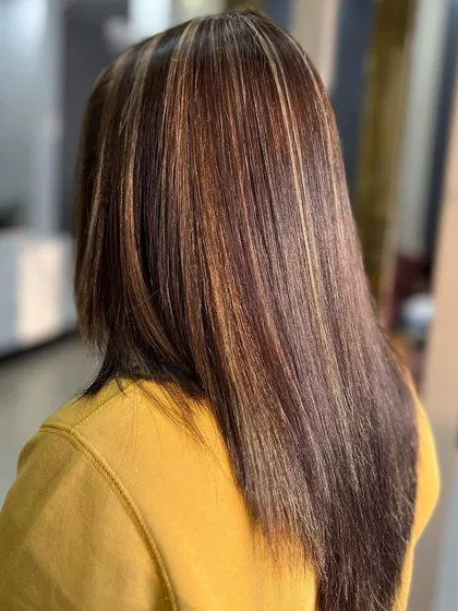 A side view of sleek, straight hair with golden blonde highlights. This shows how highlights can add brightness and interest even to a simple, straight style.