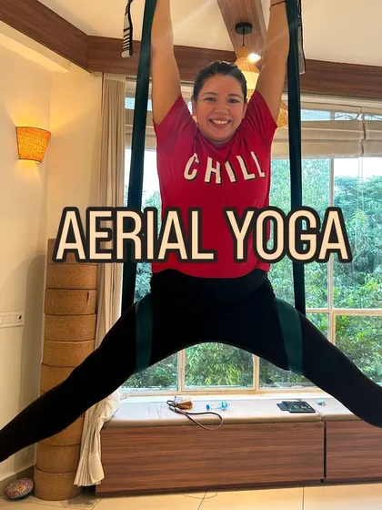 A student confidently holds a wide-legged split in the aerial hammock, framed by the beautiful greenery outside our studio window. This image perfectly blends the practice with the calming environment.