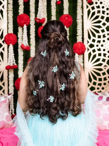 A look at the beautiful half-up, half-down hairstyle with delicate floral accessories, perfect for a Mehendi or Sangeet event.