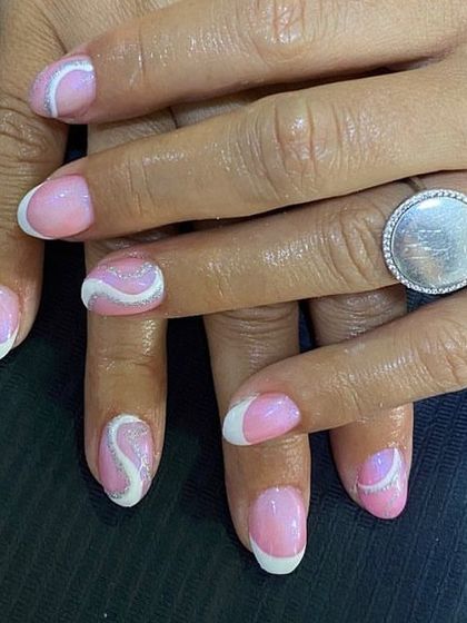 A playful design with a pink base, white tips, and a silver glitter swirl accent. It's a fun combination of a French manicure and abstract art.