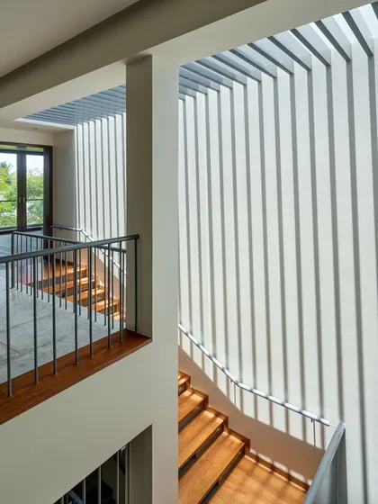 The play of light and shadow is a material we sculpt with. In our "The Mantle" project, these vertical fins cast dramatic, shifting patterns across the staircase, turning a simple transition space into a dynamic art installation.