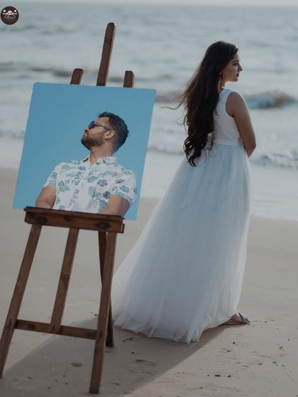 A creative concept for a beach pre-wedding shoot, using a portrait on an easel. This is a unique idea for couples who want something artistic and different.