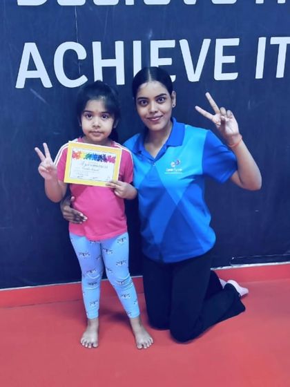 This young student and her coach celebrate her new certificate with matching peace signs.
