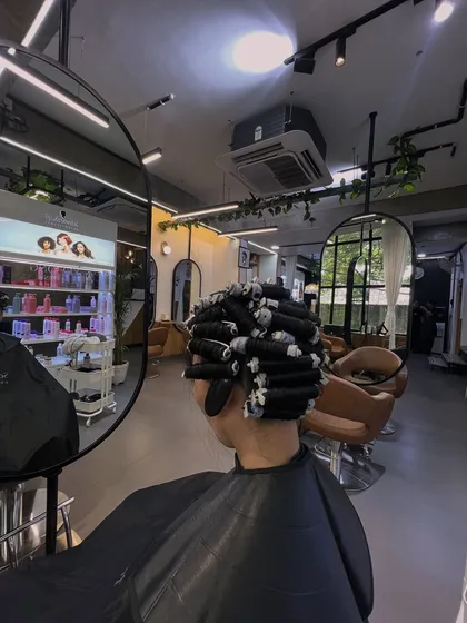 This is a behind the scenes look at the perming process. I carefully wrap sections of hair around perm rods, which is a crucial step to determine the size and shape of the final curls.