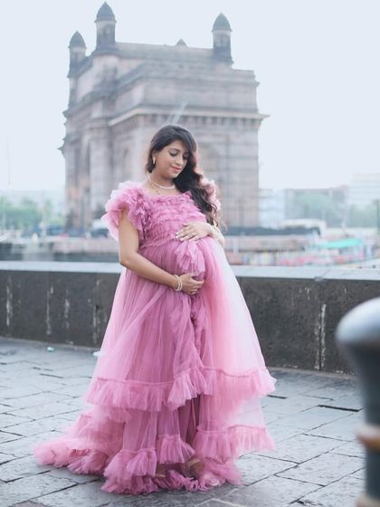 A beautiful maternity photo in front of the Gateway of India. The mom-to-be cradles her bump in our elegant pink ruffled gown.