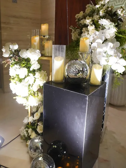 A detail shot of the "Disco Romance" theme, showing a mix of candles, disco balls, and white floral arrangements on mirrored pedestals.