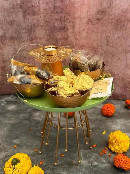 A modern and stylish take on festive gifting. This green metal stand holds bowls of treats and a flower-shaped T-light, offering a contemporary look for your Diwali celebrations.