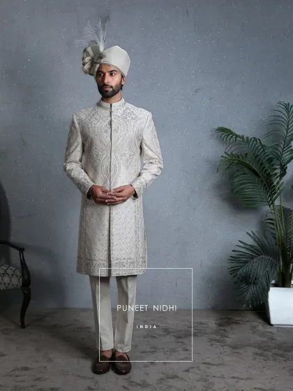 A poised stance in the ivory silk sherwani, showing the structured fit and the regal symmetry of the geometric buta motifs. This ensemble is designed for a groom who carries heritage with pride.