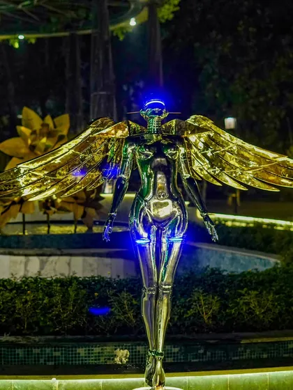 A futuristic, winged metallic sculpture stands as a bold art installation, adding a unique and unexpected element to the cocktail party decor.