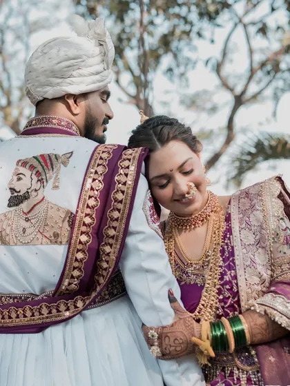 A beautiful shot from the back, focusing on the groom's custom sherwani featuring a portrait of Chhatrapati Shivaji Maharaj, and the bride's loving embrace.