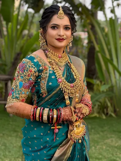 A beautiful bride in a teal Nauvari saree, with intricate gold jewellery and a soft, elegant makeup look.