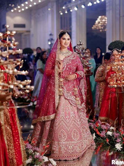 A beautiful shot of the bride during her entrance, surrounded by attendants holding candles, creating a warm and magical atmosphere.