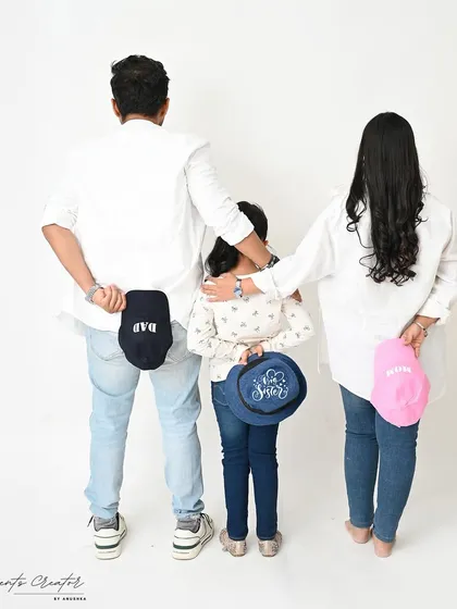 A creative and fun family announcement. The matching hats add a playful touch to this unique family portrait, revealing their roles as 'Dad,' 'Mom,' and 'Big Sister.'