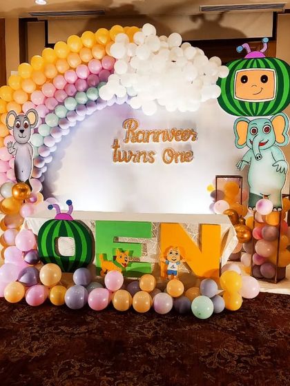 A beautiful rainbow balloon arch for a Cocomelon first birthday. This large-scale decoration includes multiple character cutouts and a personalized name sign.