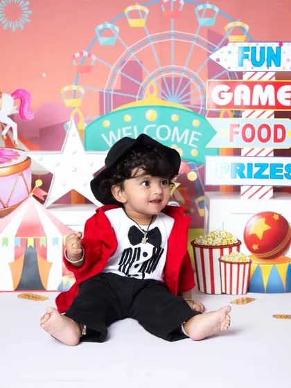 Welcome to the carnival! This vibrant, fully-styled setup is perfect for a fun-filled milestone session, complete with a colorful ferris wheel, popcorn, and a tiny ringmaster outfit.