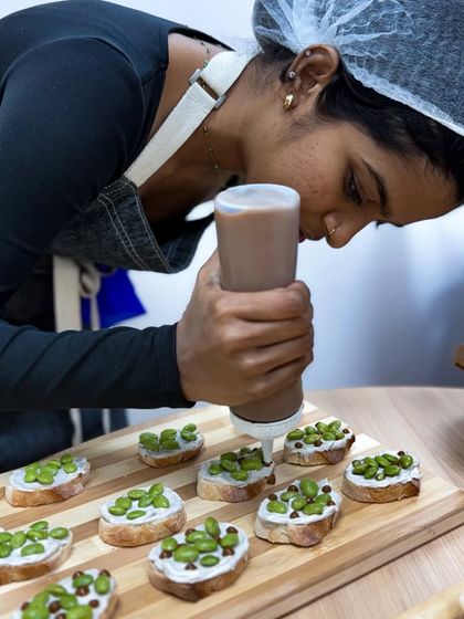 A chef adding the finishing touches to our cream cheese and edamame tartines. We love creating food that is as beautiful as it is tasty.