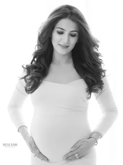 A serene and gentle solo portrait. Black and white enhances the soft light and the quiet emotion as this mother-to-be gazes lovingly at her bump.