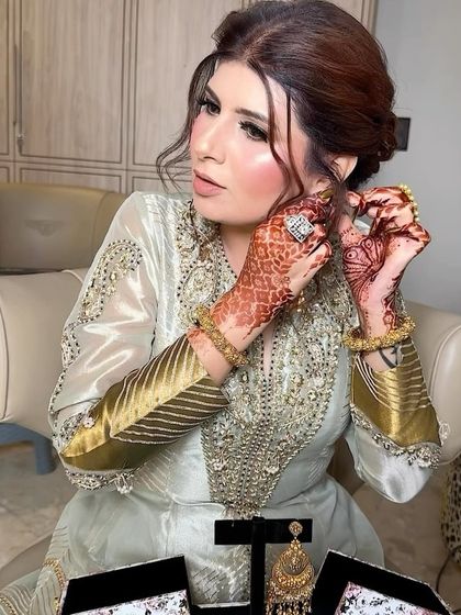 A candid moment of the client putting on her exquisite earrings. Every detail, from the makeup to the jewelry, contributes to the final stunning look.