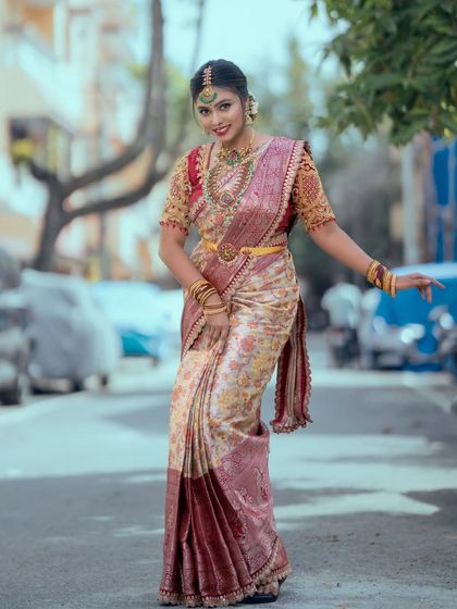 This shot captures the elegance of the bride's posture, highlighting the drape of the saree and the fall of the long necklace.