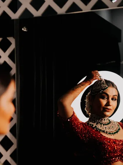 A bride looking at her reflection as she gets ready. The creative use of the halo light and the mirror creates a striking and modern portrait.