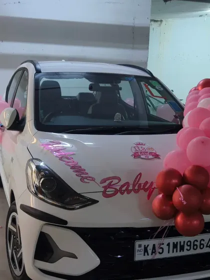 Another shot of the decorated car, showing the "Welcome Baby" vinyl sticker and the pink balloon arrangements on the hood and side mirrors.